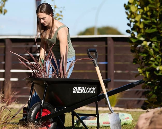 Person gardening and wheelbarrow loaded with greenlife 