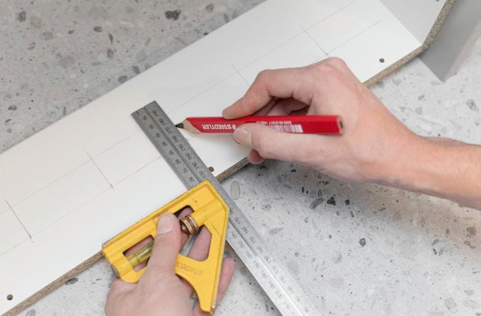 Using pencil and ruler to mark a cabinet.