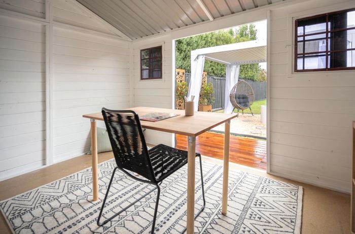 Interior shot of a backyard shed with wooden table, rug and clever cube storage rack