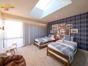 Blue bedroom with a check wallpapered wall and twin beds with blue linens. Opposite is a brown leather bean bag and small kids table. Above the beds are various horse artworks arranged sporadically.