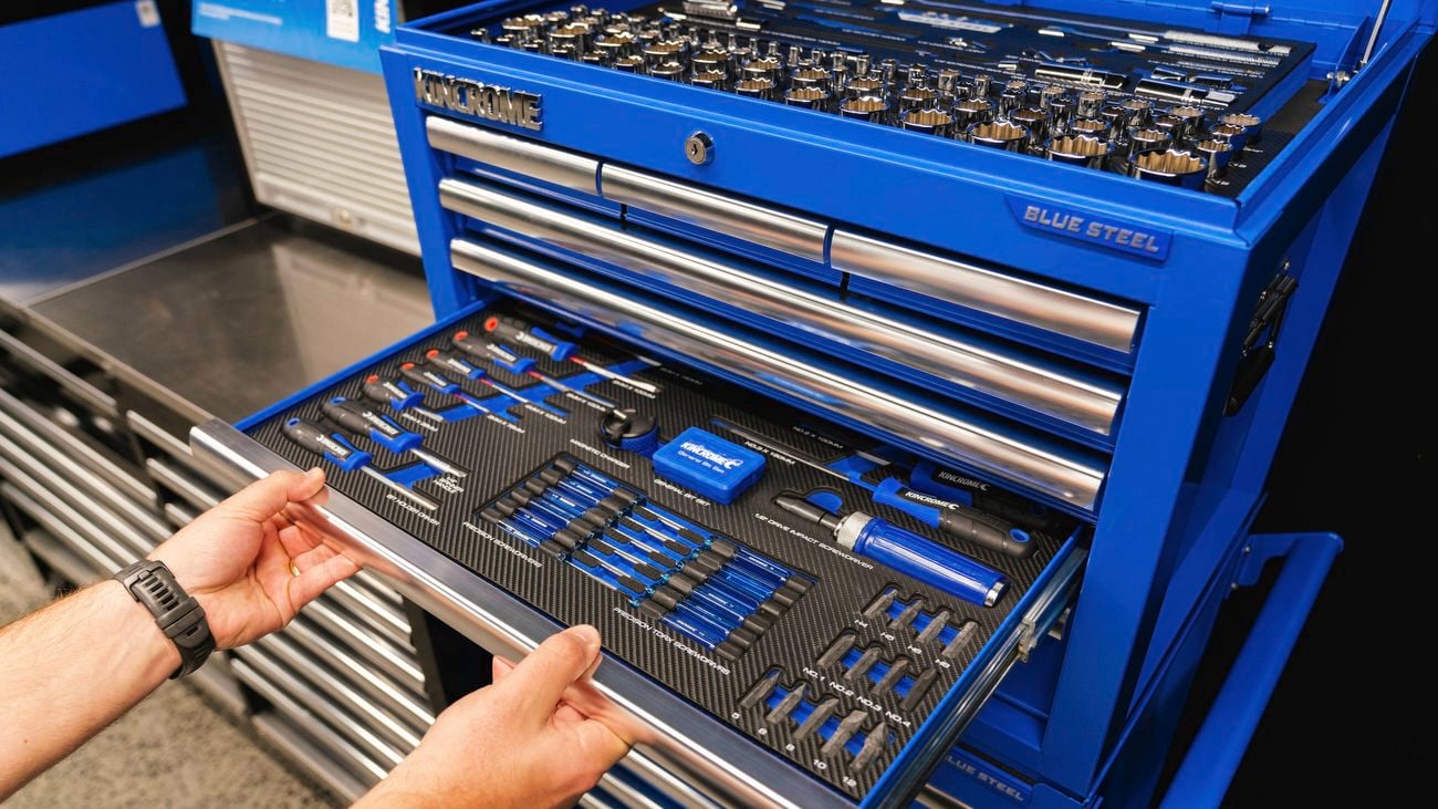 Blue kincrome steel tool storage unit, seeing hand opening the sliding draws