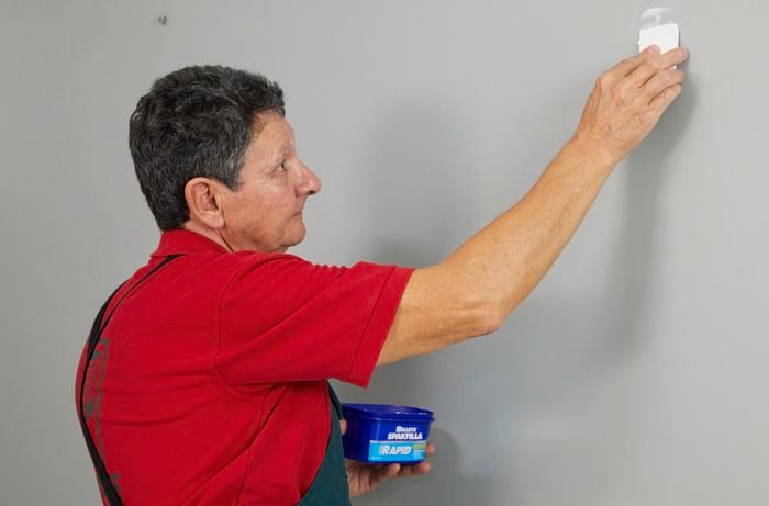 A man uses Selleys Spakfilla to fill a hole in an interior wall.