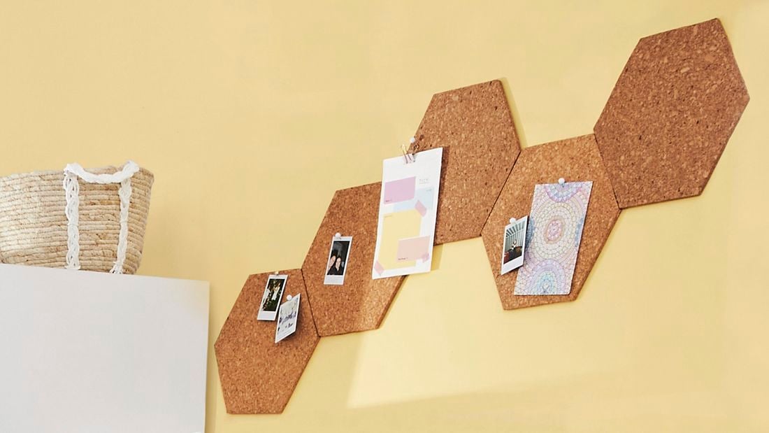 Corkboard organiser with photos pinned to it.