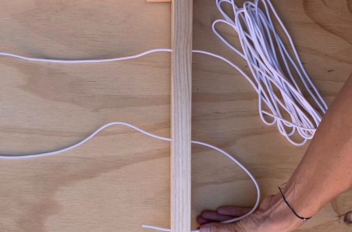 Cord being threaded through holes in a drying rack