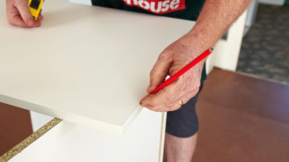 A person drawing a line on a laminated panel
