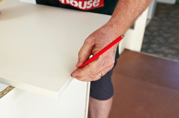 A person drawing a line on a laminated panel