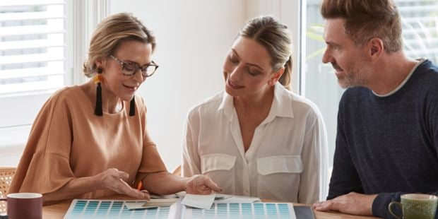 A colour consultant talking to two customers with a colour chart book.