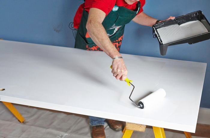 Person painting door with paint roller.