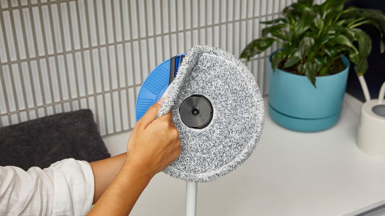 Person cleaning their circular mop head with a scrubbing roller.
