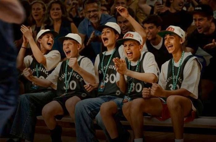 Kids wearing basketball merchandise celebrating on the bench.