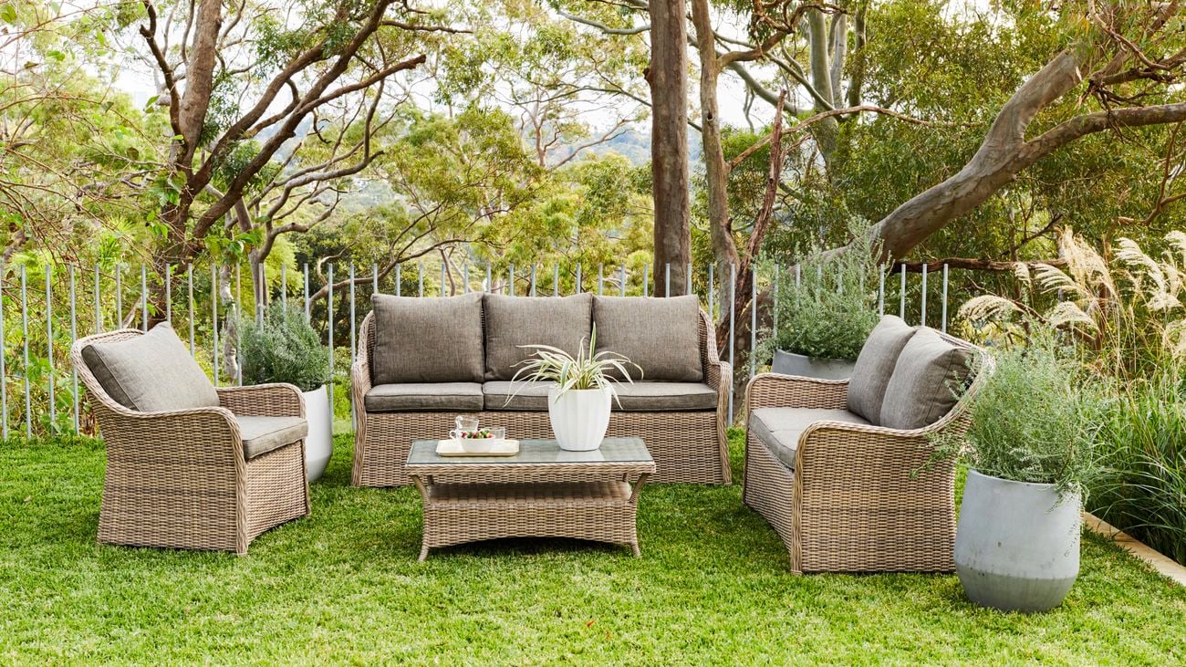 Wicker outdoor lounge setting including a lounge, two arm chairs and a coffee table.