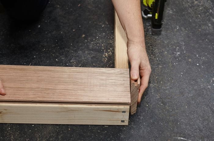 Person attaching tongue to timber bedhead frame.