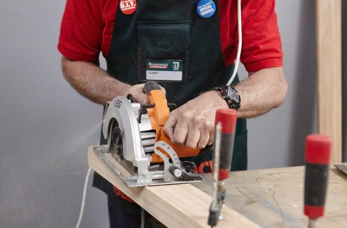 A chair leg being cut along a taper with a circular saw by a Bunnings team member