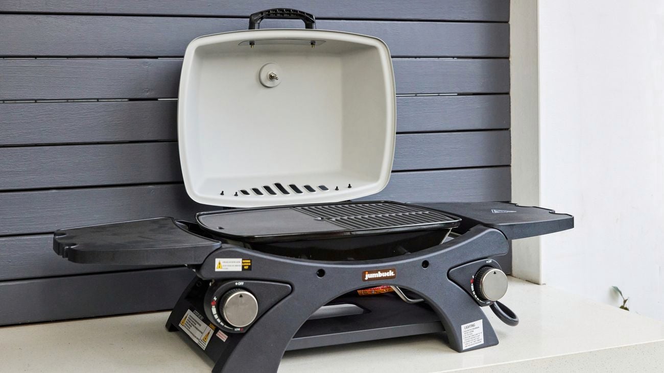 A small, portable BBQ rests on a white benchtop with top open