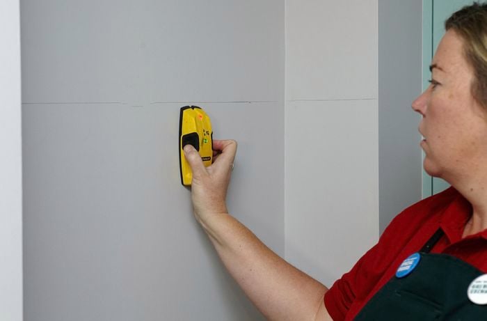 Person using stud finder on wall.