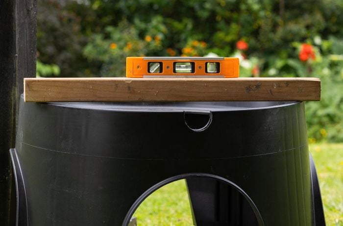 A black step stands on grass with a plank of wood placed horizontally on top of it.
