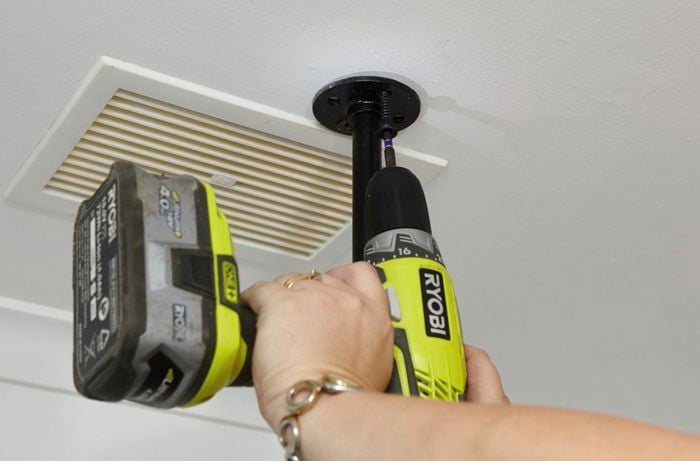 A pipe fitting being screwed into the ceiling