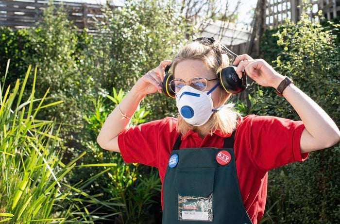 Person wearing ventilation mask putting on earmuffs.