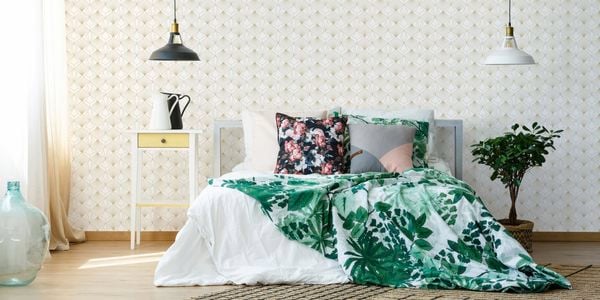 Bedroom with Graham & Brown wallpaper, bed with light coloured furnishings and two-bedroom hanging lights.