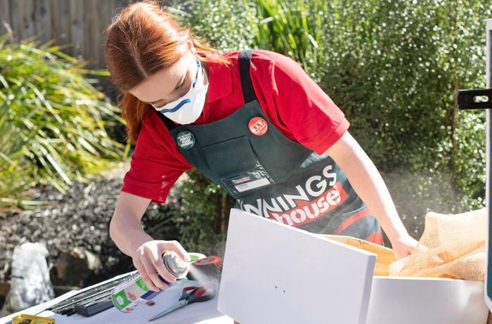 Woman spraying adhesive on the front of a drawer