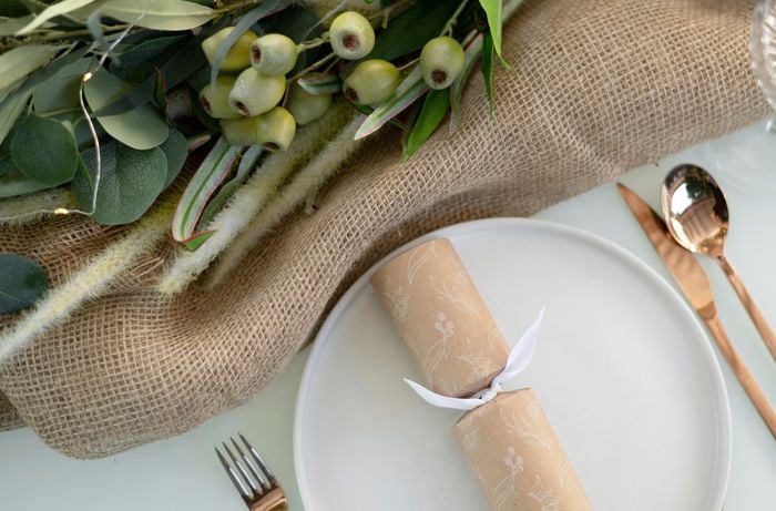 Birds eye view of a table with hessian tablecloth, Christmas bon bon, cutlery and plants.