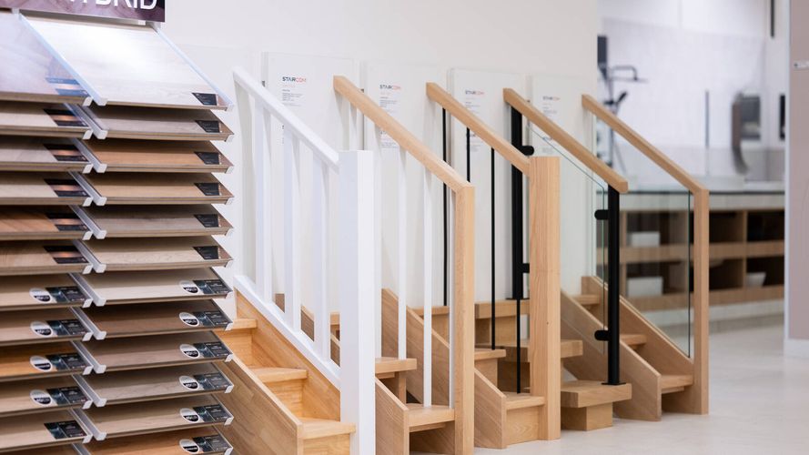Display of staircase and balustrade systems showcasing timber, metal and glass railing options alongside flooring samples.
