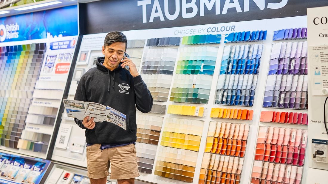    a {     text-decoration: none;     color: #464feb; } tr th, tr td {     border: 1px solid #e6e6e6; } tr th {     background-color: #f5f5f5; }     A person standing in front of a Bunnings paint display wall while holding a brochure and talking on the phone.