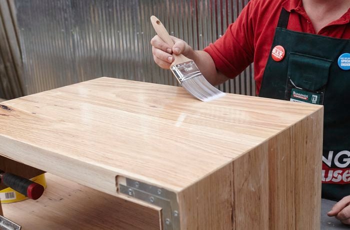 A person varnishing a timber vanity unit