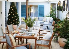 A table and chairs in an outdoor area set up ready for a christmas party.