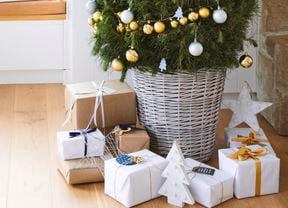 Christmas tree with presents underneath and a window seat next to it.
