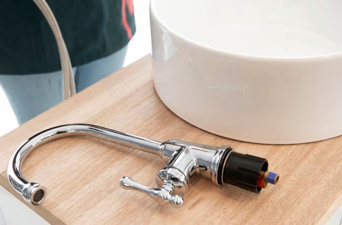 Unconnected tap laying on the vanity beside a sink