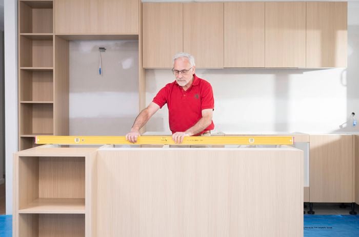 A Bunnings Team Member is using a spirit level to ensure the kitchen cabinets are levelled and stable.