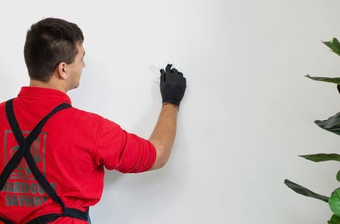 Person wiping white wall with cloth.