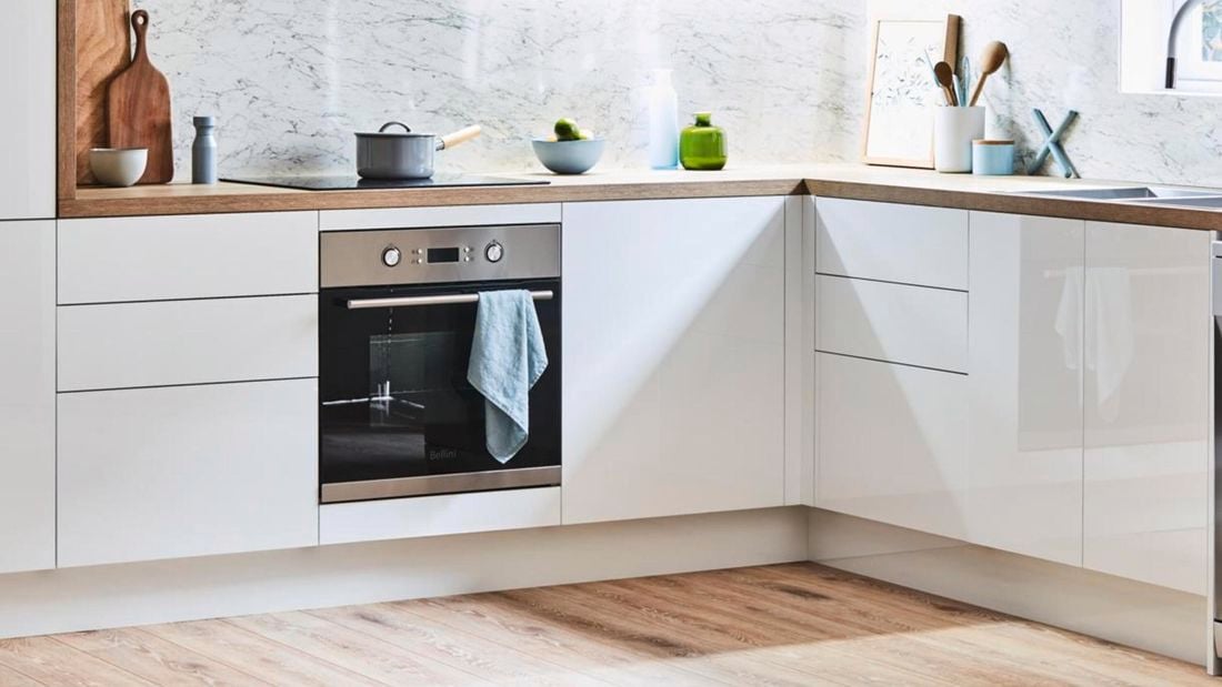 Modern kitchen with white cabinets and splashback, coupled with timer benchtops.