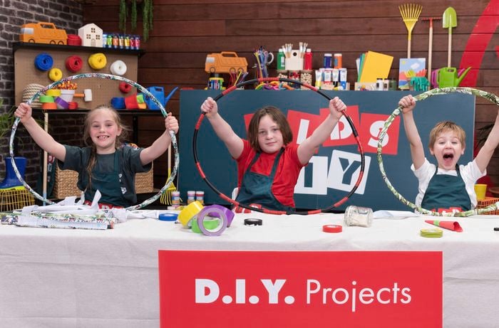 Three excited kids are holding up their decorated hula hoops