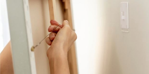 a person hanging a canvas on a hook