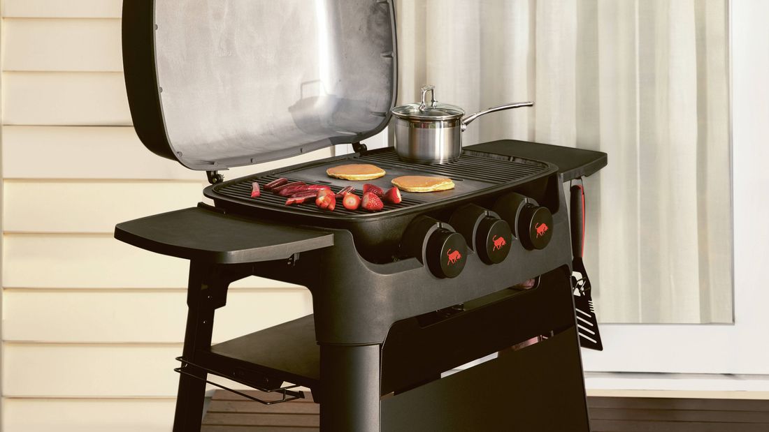 Black barbecue with strawberries and pancakes cooking on a wooden deck