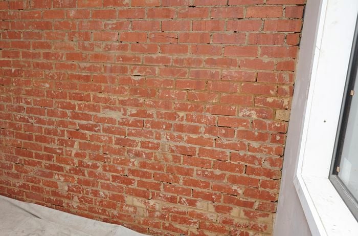 A brick wall prepared for plastering with drop sheet below