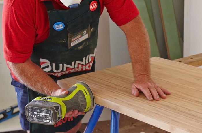 A benchtop being sanded by a Bunnings team member