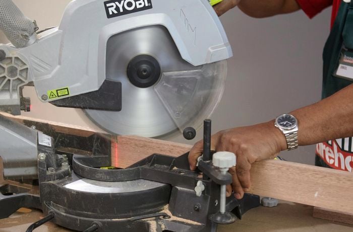 Person using drop saw to cut piece of timber