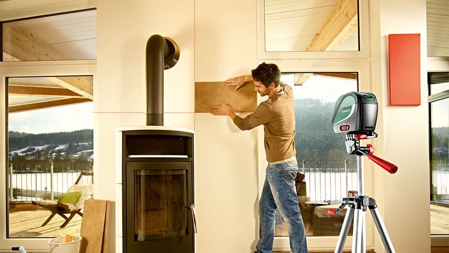 Person using laser level to place wall panel