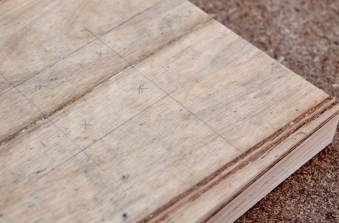 Pencil markings on the wooden coat rack base, showing where the centre of the base is and four points for anchoring screws