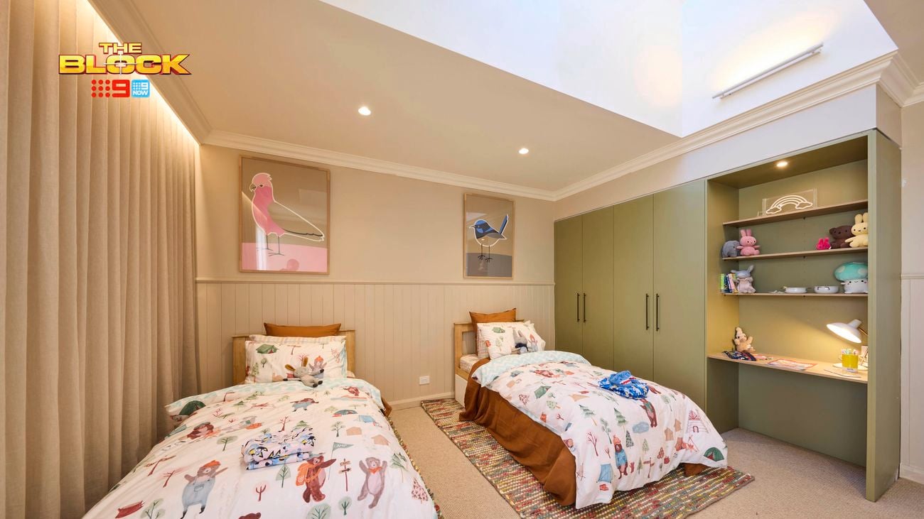 Olive and cream kids bedroom with twin beds and animal print linen, 2 coloured rugs and a wardrobe and desk on the opposite wall.