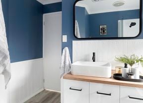 Renovated bathroom with a mirror, basin, towels and blue walls