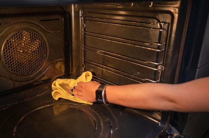 Wiping down the inside of the oven using a microfibre cloth.