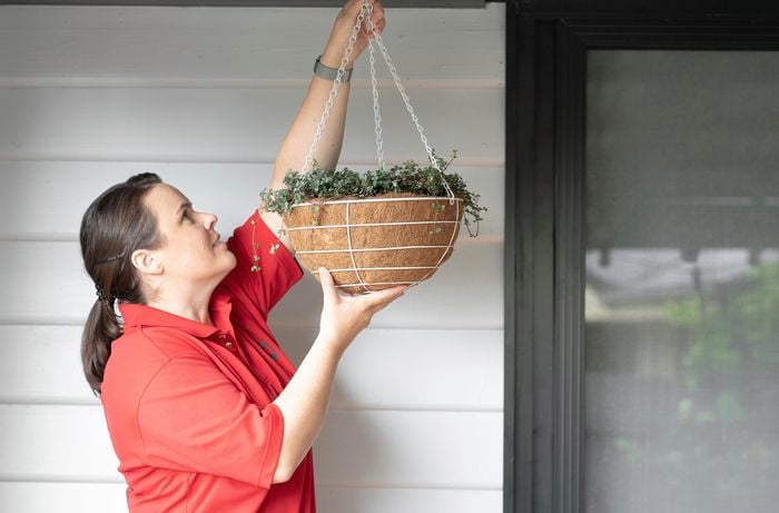 A Bunnings team member hanging a hanging basket from a roof mounted hook