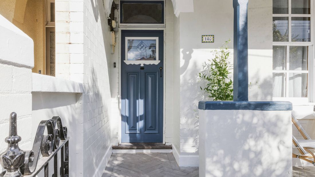 Freshly painted heritage home entryway with a blue front door and white brickwork.