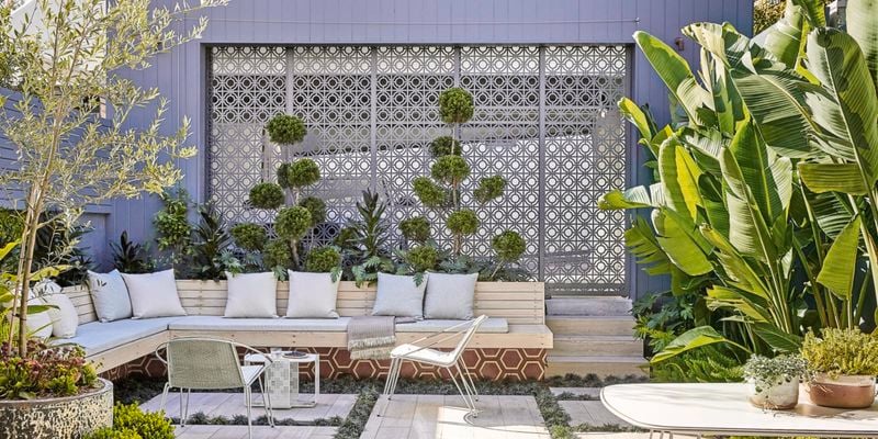 Outdoor area with bench seat, chairs, paving and plants.