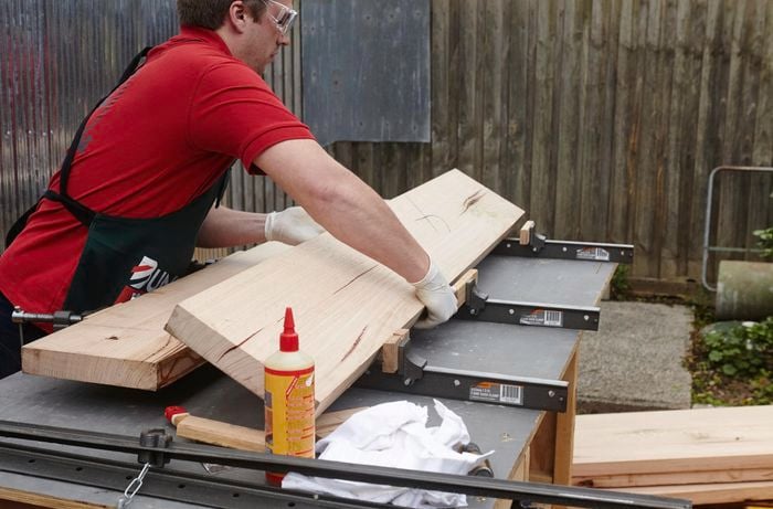 A person placing two lengths of timber into bench clamps