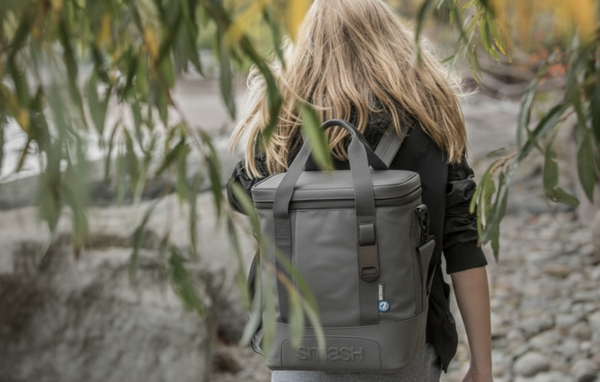 a lady wearing a large cooler bag with gum trees in the back ground